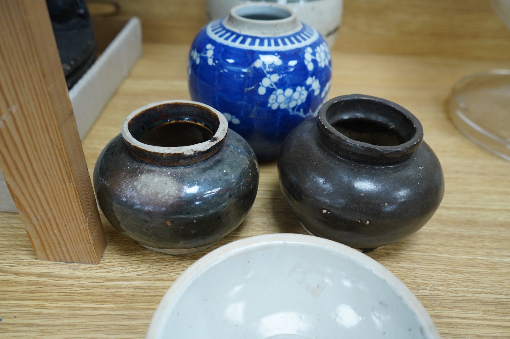 A collection of Chinese pottery jars and a decorated plate, tallest jar 18cm high